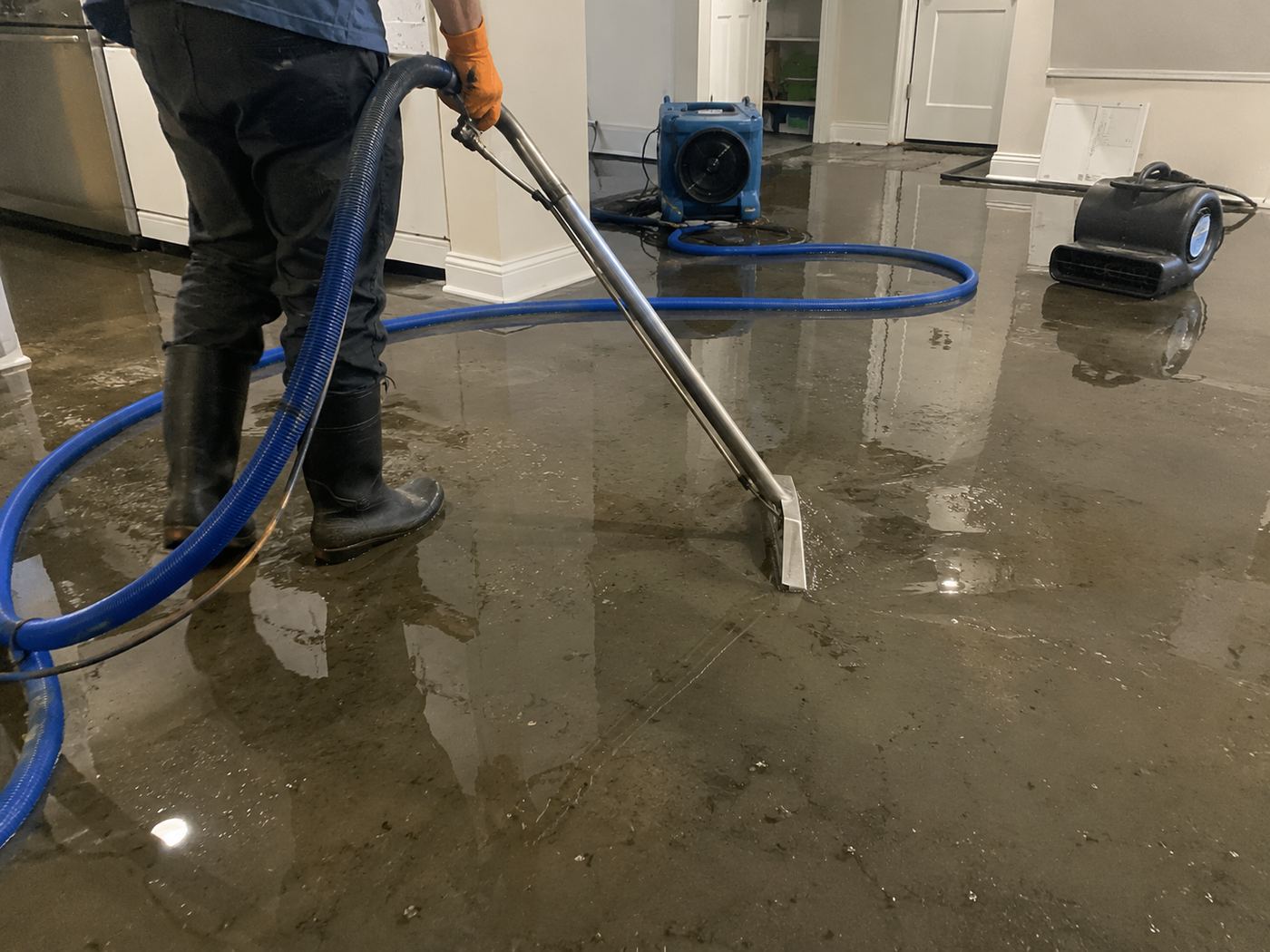 Water damage restoration technician using industrial extraction equipment in a Fernandina Beach home